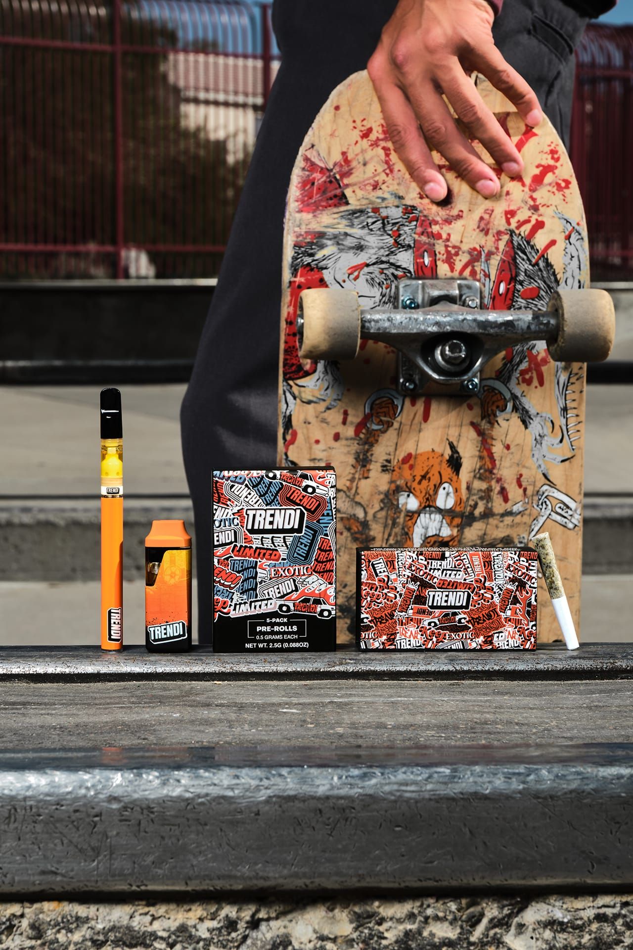 TRENDI vape pen, all-in-one, pre-roll packs and a single pre-roll lined up on a skatepark ledge, beside a skater holding a board